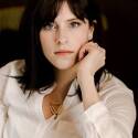 Kelley Brown is wearing a white button up shirt and a serious expression.